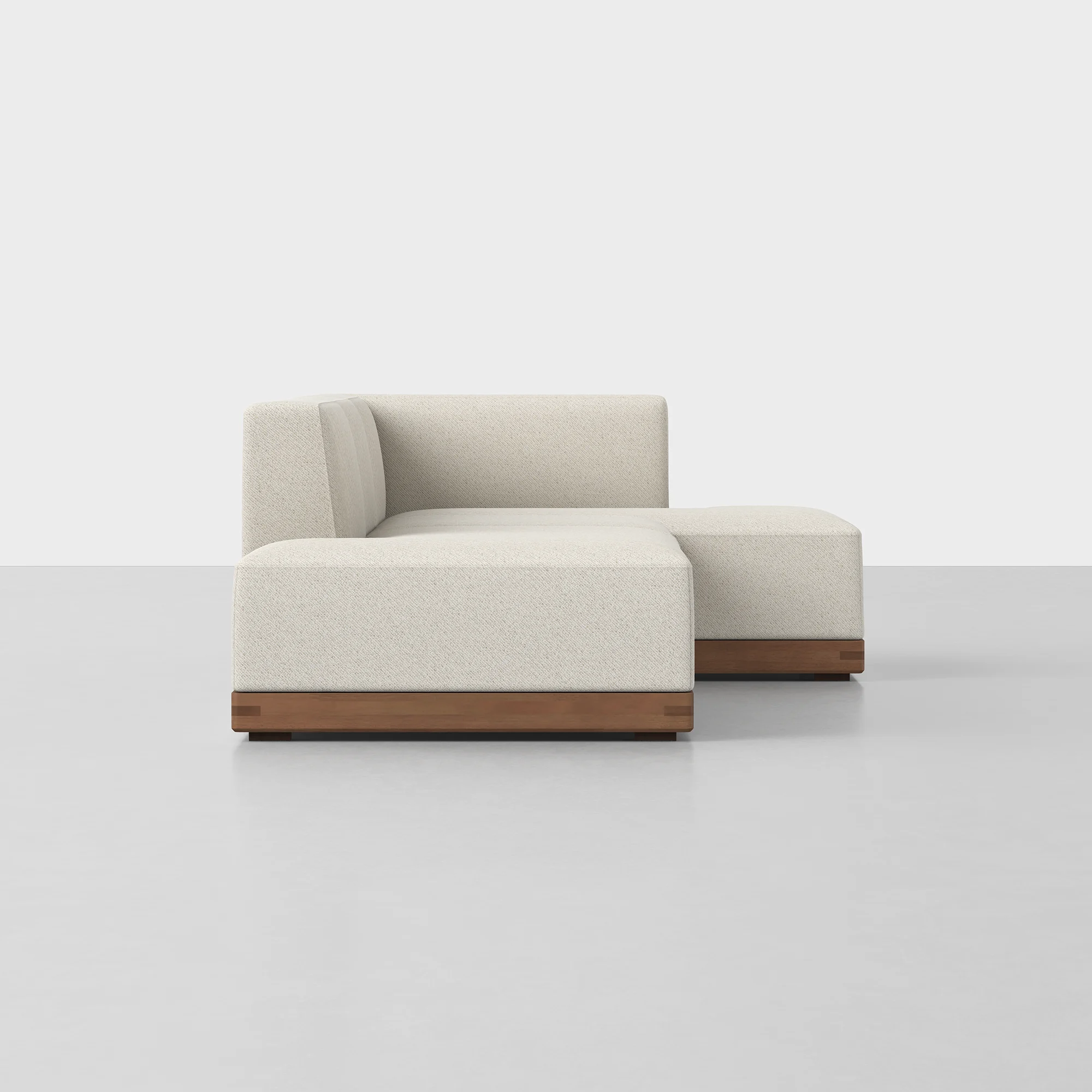 Beige L-shaped sectional sofa with wooden base on a light gray floor against a plain white background.