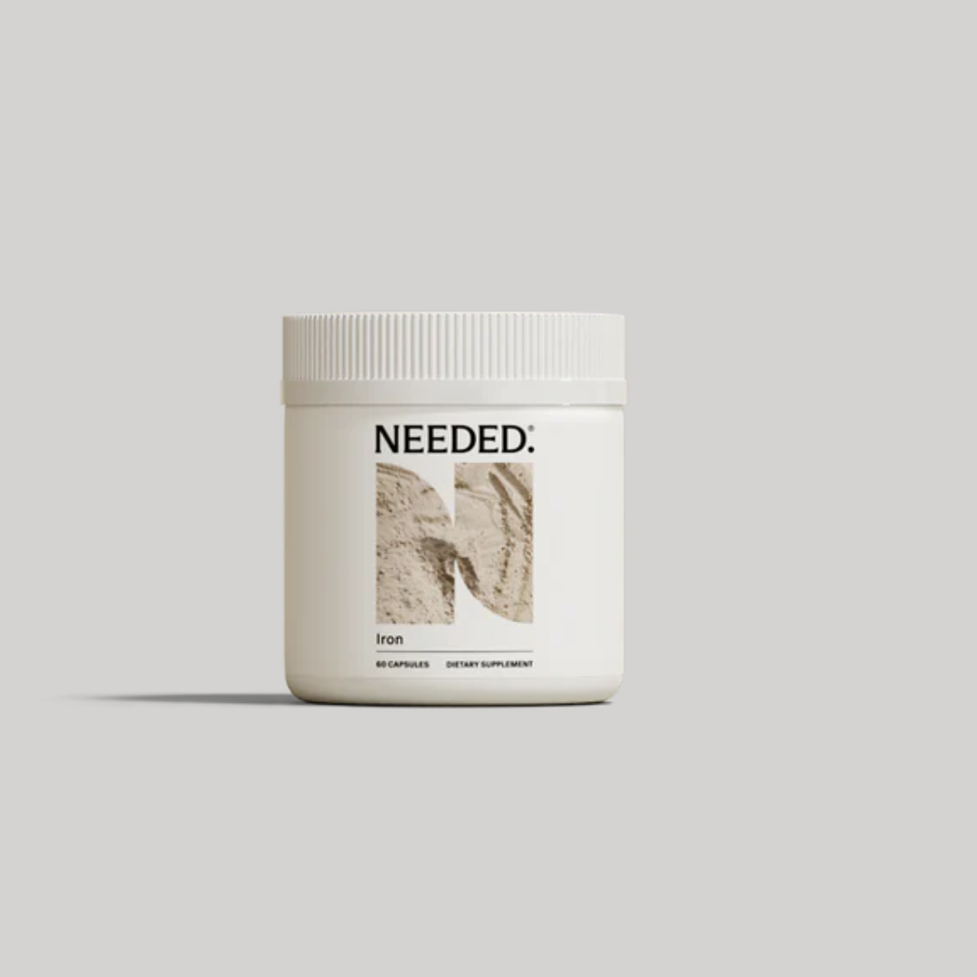 A white container labeled "NEEDED: Iron" with an abstract design on the front, containing 60 capsules of dietary supplement, set against a plain gray background.