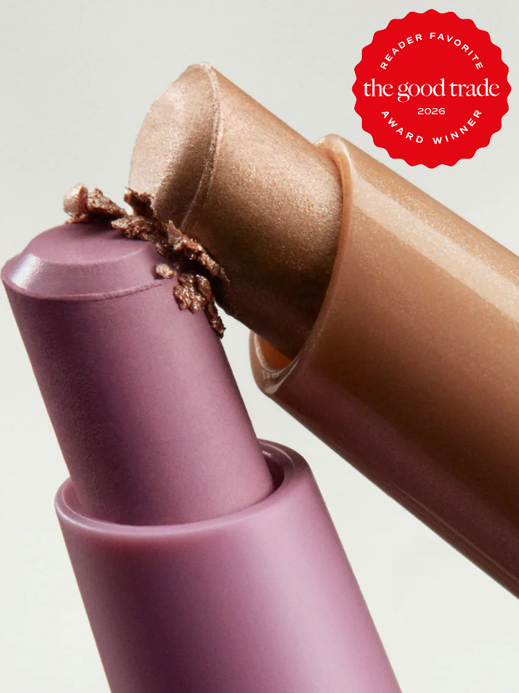 Close-up of two lipsticks, one mauve and one metallic gold, with an award emblem in the top right corner reading "The Good Trade Reader Favorite Award Winner 2026.