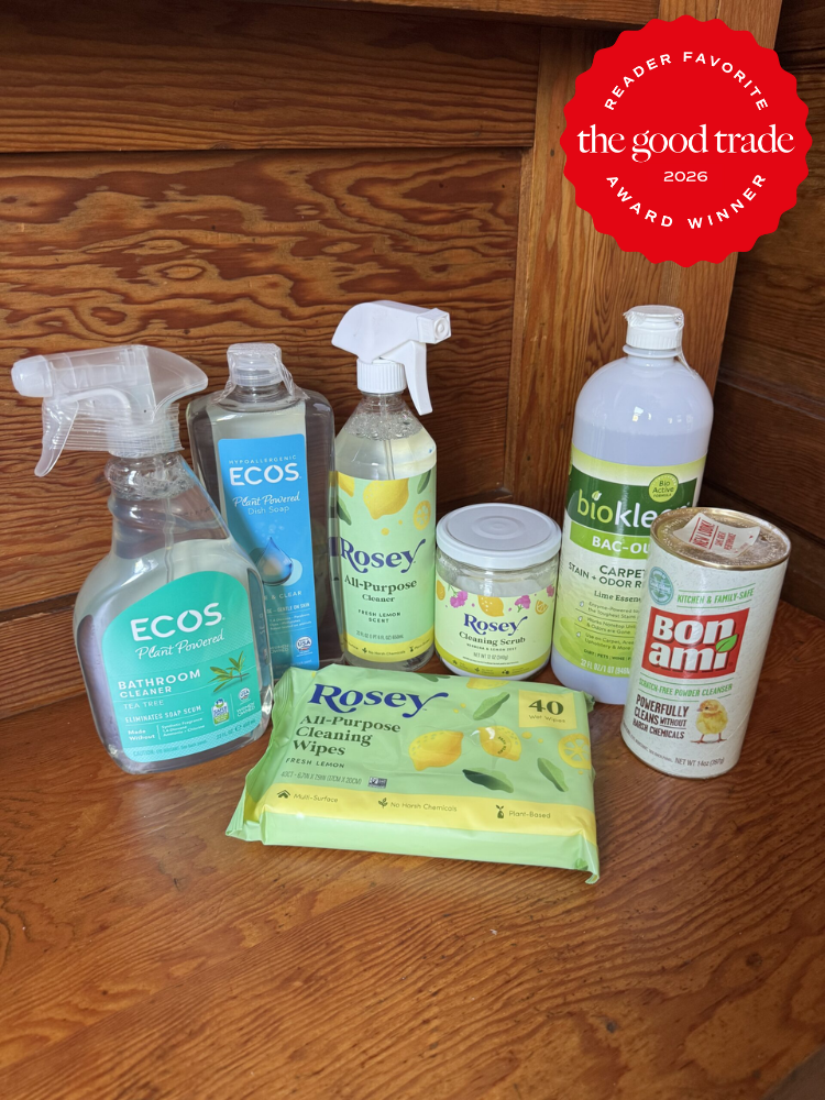 A selection of eco-friendly cleaning products, including sprays, wipes, powder, and liquid cleaners, arranged on a wooden surface with an award badge in the top right corner.