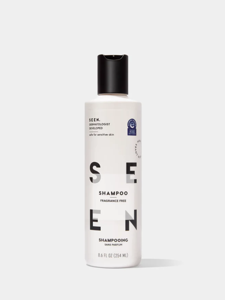 A white 8.6 fl oz bottle of SEEN fragrance free shampoo with a black flip-top cap, labeled as dermatologist developed and safe for sensitive skin.