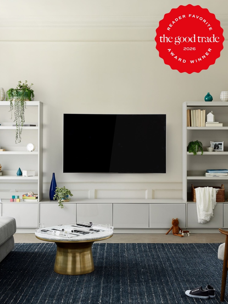 A modern living room with a wall-mounted TV, white shelves, a blue rug, and a round coffee table; a red "Reader Favorite" award badge is in the top right corner.
