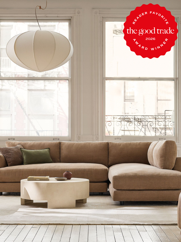 A modern living room features a beige sectional sofa, a round coffee table, and a white pendant lamp beside large windows. A red award seal is displayed in the top right corner.