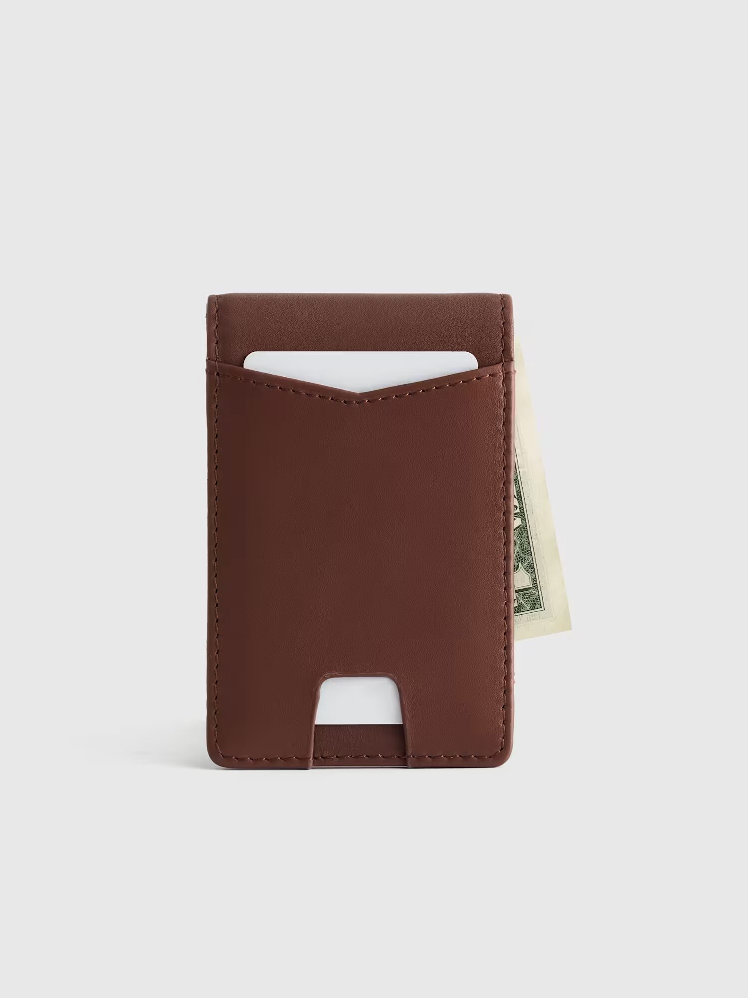 A brown leather card holder with a card in the front slot and a US dollar bill partially sticking out from the back.