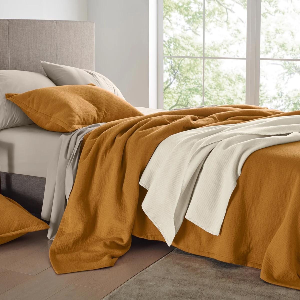 A bed with orange blankets and pillows.
